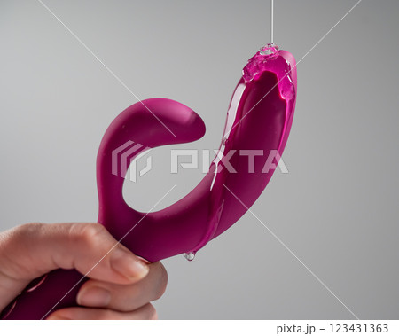Lube pouring on pink dildo on white background.  123431363