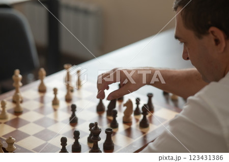 Caucasian man thinking about a chess move.  123431386
