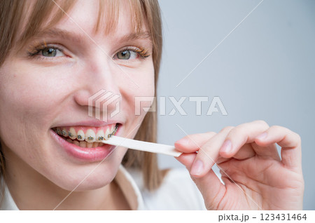 Young woman with metal braces on her teeth is chewing gum. The girl is eating gummy candy Young woman with metal braces on her teeth is chewing gum. The girl is eating gummy candy 123431464