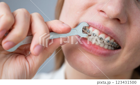 The woman jokingly tightens the wire of the brakes with a wrench. Bite correction device The woman jokingly tightens the wire of the brakes with a wrench. Bite correction device 123431500