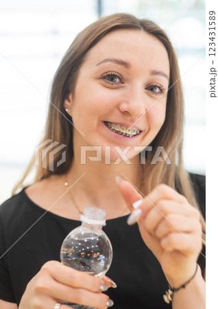 Caucasian woman with braces on her teeth drinking water. Caucasian woman with braces on her teeth drinking water. 123431589