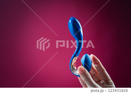 Lube pouring onto blue sex toy on pink background. Lube pouring onto blue sex toy on pink background. 123431828