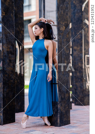 Beautiful asian ballerina in blue dress and pointe shoes posing outdoors. Vertical photo.  123431952