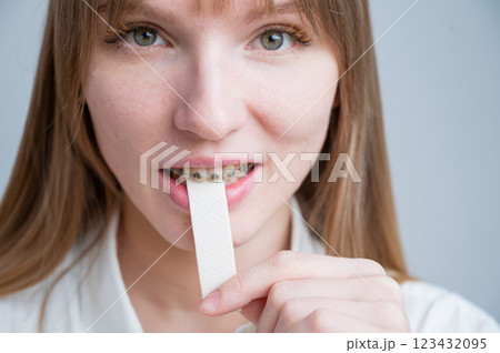 Young woman with metal braces on her teeth is chewing gum. The girl is eating gummy candy 123432095