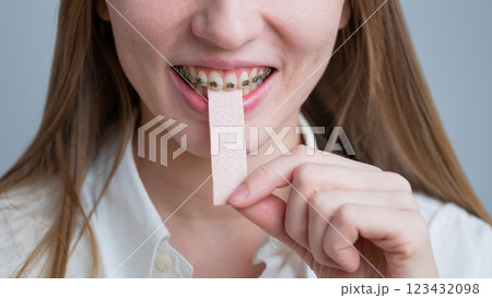 Young woman with metal braces on her teeth is chewing gum. Young woman with metal braces on her teeth is chewing gum. 123432098