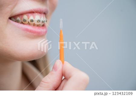 Unrecognizable Caucasian woman cleans braces with a brush. Close-up of female teeth with brackets 123432109