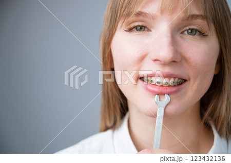 The woman jokingly tightens the wire of the brakes with a wrench. Bite correction device 123432136