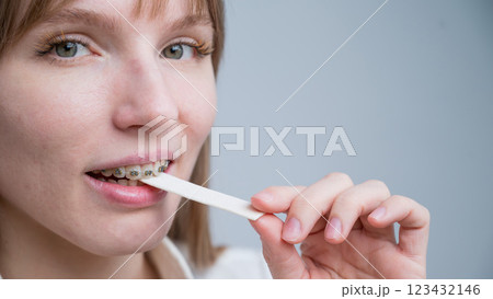 Young woman with metal braces on her teeth is chewing gum. The girl is eating gummy candy 123432146