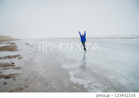 Caucasian woman in a blue sweater is skating on a frozen lake. The figure skater performs the program. 123432238
