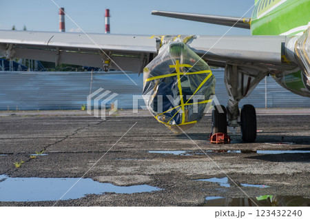 An airplane turbine undergoing repairs is wrapped in film.  123432240