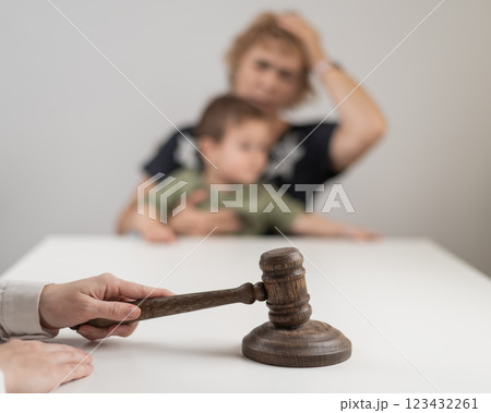A judge hits a gavel against the backdrop of an elderly woman holding a child.  123432261