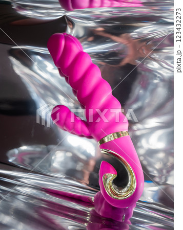 Sex toy on a metal background in the reflections of light.  123432273