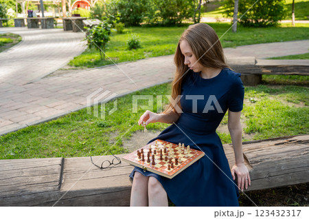 Caucasian woman playing chess outdoors. Caucasian woman playing chess outdoors. 123432317