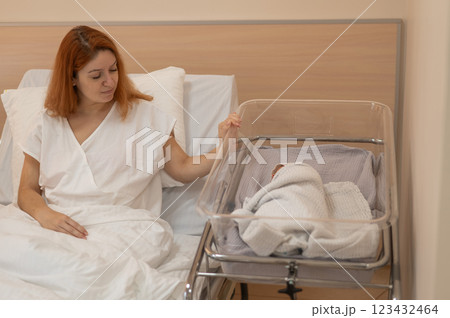 A young mother admires her newborn son in the maternity hospital.  123432464