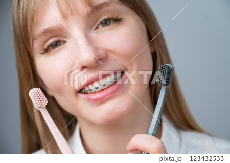 Caucasian woman in braces holding toothbrushes on white background. Caucasian woman in braces holding toothbrushes on white background. 123432533