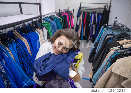 Top view of a chubby-cheeked woman holding an armful of clothes in a plus size store. Top view of a chubby-cheeked woman holding an armful of clothes in a plus size store. 123432534