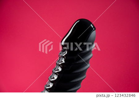 Lube pouring on black dildo on pink background. Lube pouring on black dildo on pink background. 123432846