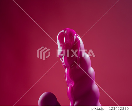 Lube pouring on pink dildo on pink background. Lube pouring on pink dildo on pink background. 123432850