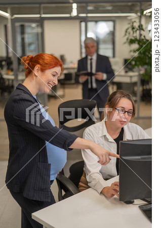 Caucasian pregnant woman giving instructions to subordinate in office. Vertical photo.  123433056