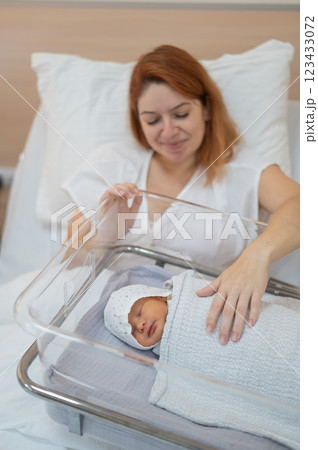 A young mother admires her newborn son in the maternity hospital. A young mother admires her newborn son in the maternity hospital. 123433072