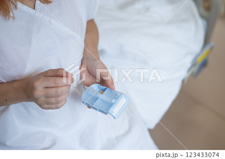 Close up of hands. Woman holding pillbox in hospital.  123433074