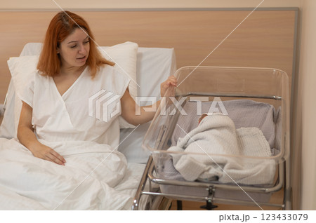 A young mother admires her newborn son in the maternity hospital.  123433079