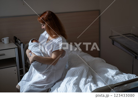 Caucasian woman holding newborn son while sitting on couch in maternity hospital ward. Caucasian woman holding newborn son while sitting on couch in maternity hospital ward. 123433080