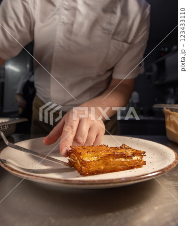 Professional chef plating a delicious potato gratin Professional chef plating a delicious potato gratin 123433110