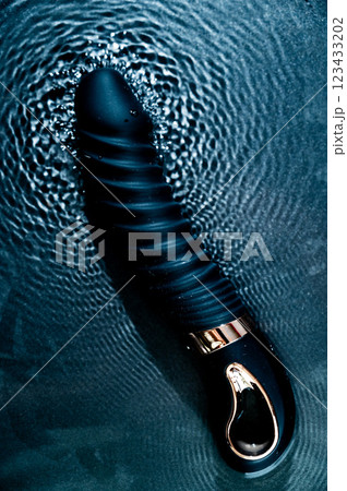Black silicone vibrator in water. Circles on water around sex toy. Black silicone vibrator in water. Circles on water around sex toy. 123433202