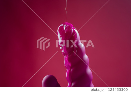Lube pouring on pink dildo on pink background.  123433300
