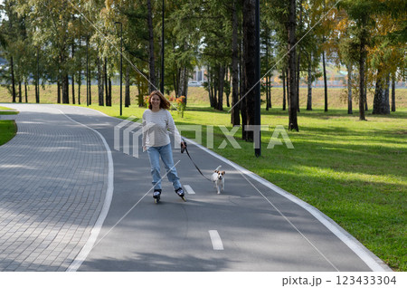 Caucasian woman roller skating with her jack russell terrier dog in park. Caucasian woman roller skating with her jack russell terrier dog in park. 123433304