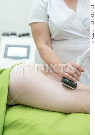 Caucasian woman on hardware anti-cellulite massage. Thigh cavitation procedure. Caucasian woman on hardware anti-cellulite massage. Thigh cavitation procedure. 123433411