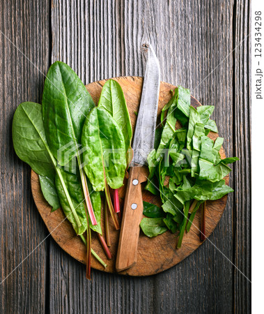 Slicing green sorrel leaves on a rustic wooden cutting board 123434298