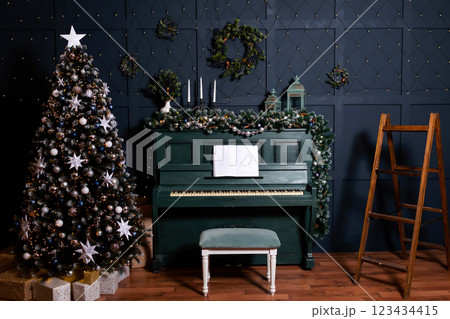 green piano blue wall decorated with christmas tree decor. classic christmas photo zone with piano 123434415