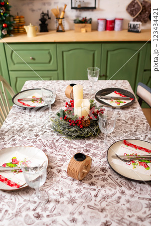 New Year's table setting in a photo studio. Plates with glasses on a Christmas tablecloth 123434421