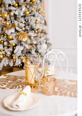 New Year's table setting in a photo studio. Plates with glasses on a Christmas tablecloth New Year's table setting in a photo studio. Plates with glasses on a Christmas tablecloth 123434528