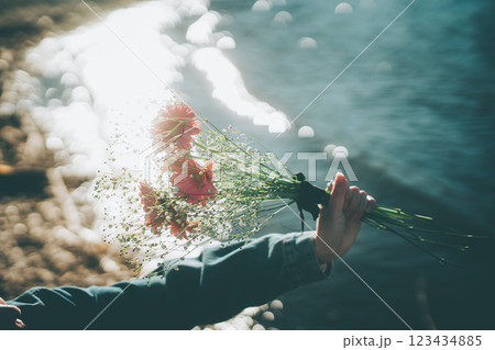 キラキラした水面とピンクの花束　手元　シネマティック　フィルム風 123434885