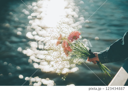 キラキラした水面とピンクの花束　手元　シネマティック　フィルム風 123434887