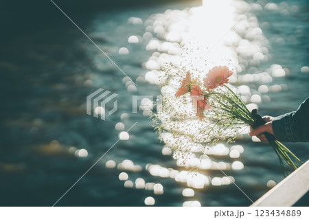キラキラした水面とピンクの花束　手元　シネマティック　フィルム風 123434889