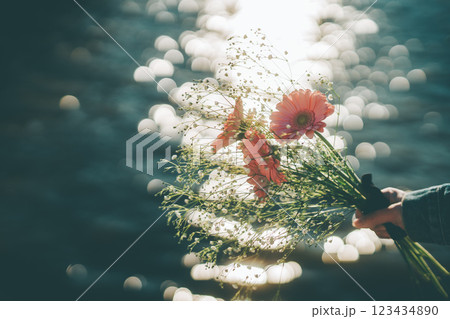 キラキラした水面とピンクの花束　手元　シネマティック　フィルム風 123434890