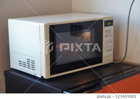 side view white microwave oven placed on an orange and black refrigerator, white wall background, object, hot, technology, copy space side view white microwave oven placed on an orange and black refrigerator, white wall background, object, hot, technology, copy space 123435002