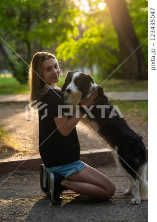 Young Caucasian woman hugging her border collie dog while walking in the park. Young Caucasian woman hugging her border collie dog while walking in the park. 123435047