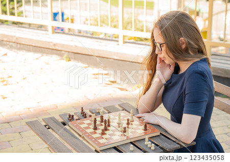 Caucasian woman playing chess outdoors. 123435058