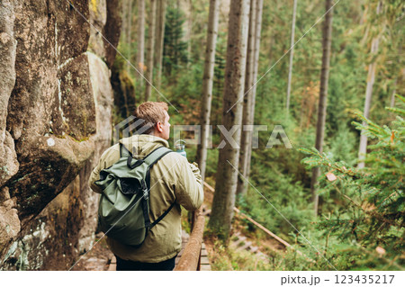 Young 30s man hiking in nature. Travel, adventure. Concept of an active lifestyle. High quality photo. Back view. Fall autumn hiker man outdoor at nature forest 123435217