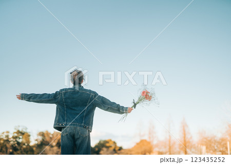 夕方の霞んだ青空を見上げて手を広げる女性の後ろ姿 夕方の霞んだ青空を見上げて手を広げる女性の後ろ姿 123435252
