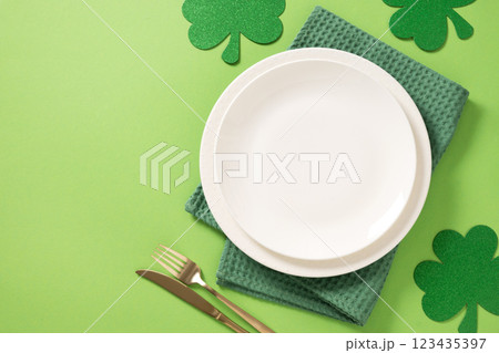 St Patrick's Day table setting with white plate and clover leaves on light green background. View from above. Copy space. 123435397