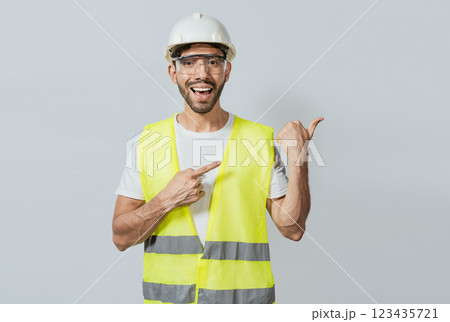 Construction engineer with vest pointing at an advertisement. Engineer man pointing to side. Builder engineer pointing finger to the right isolated, Portrait of engineer man pointing aside 123435721
