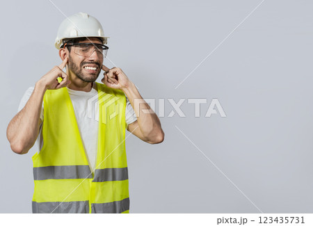 Engineer with ear pain isolated, Young engineer covering his ears isolated, Builder man with ear pain, Concept of engineer covering his ears with pain expression. Engineer with ear pain isolated, Young engineer covering his ears isolated, Builder man with ear pain, Concept of engineer covering his ears with pain expression. 123435731