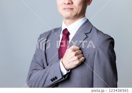 グレーのスーツを着て胸に手を当てるミドル男性ビジネスマン 123436561