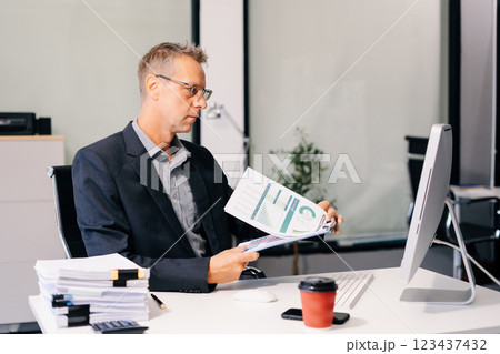Mature male businessman working at office with laptop and documents on desk, financial adviser analyzing data. Mature male businessman working at office with laptop and documents on desk, financial adviser analyzing data. 123437432